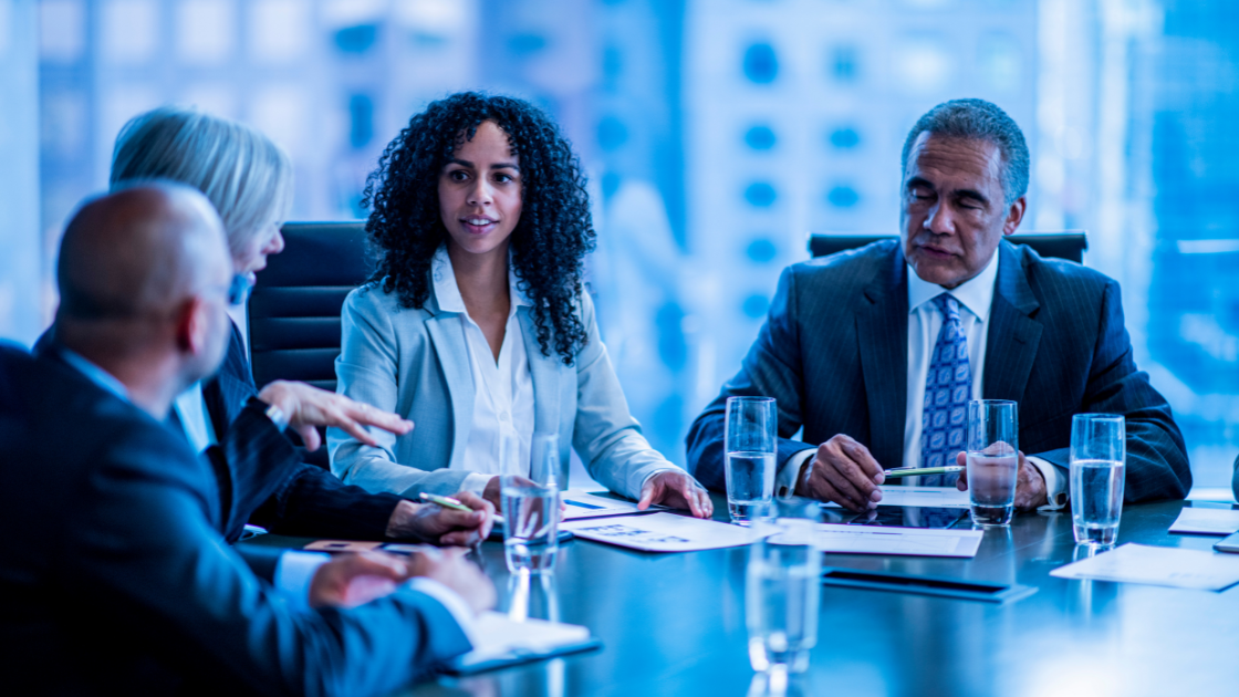 Group of professionals engaged in a discussion during a business meeting in a conference room.