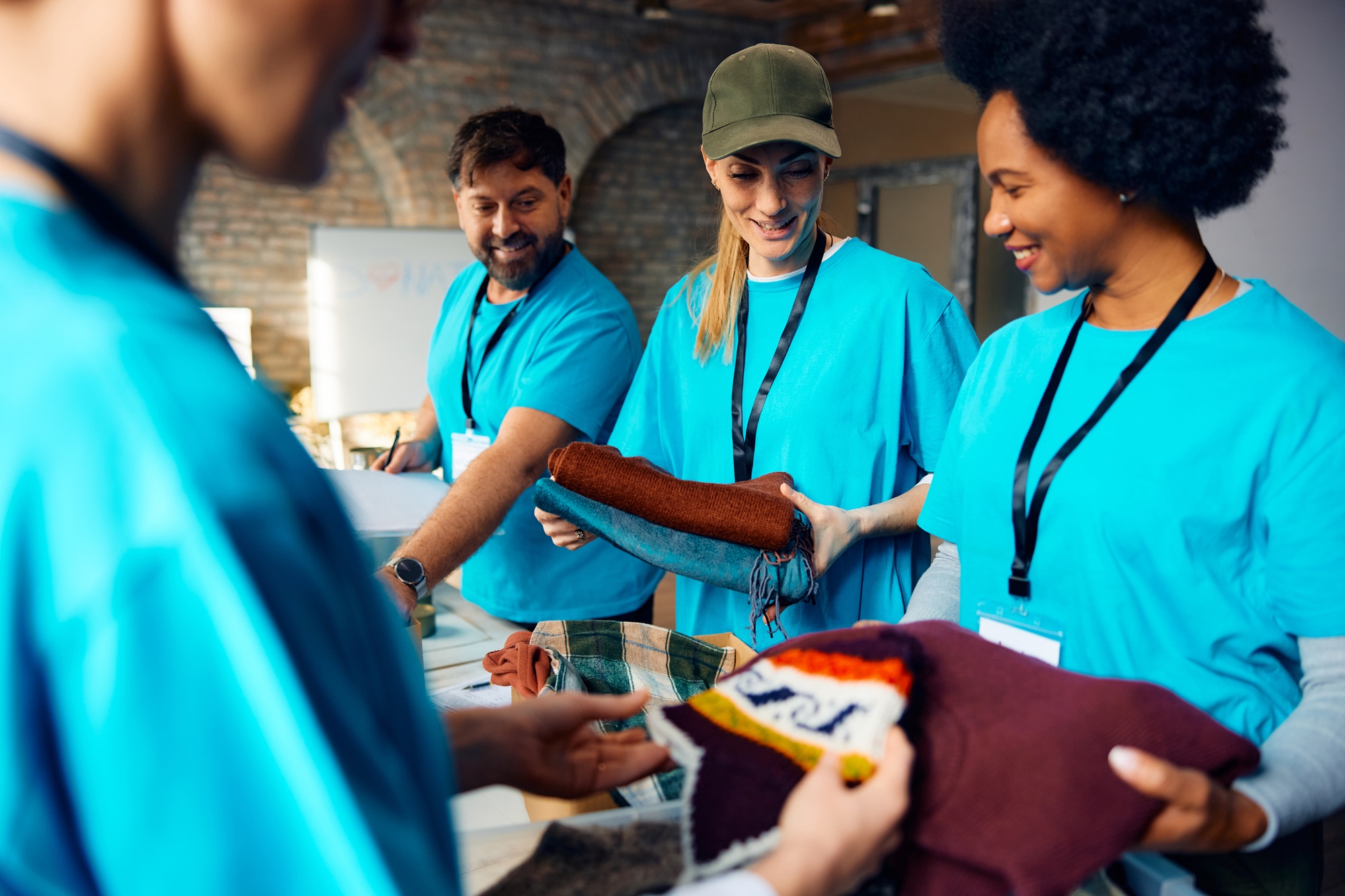 Multiracial group of people sorting clothes while working as volunteers at community center.