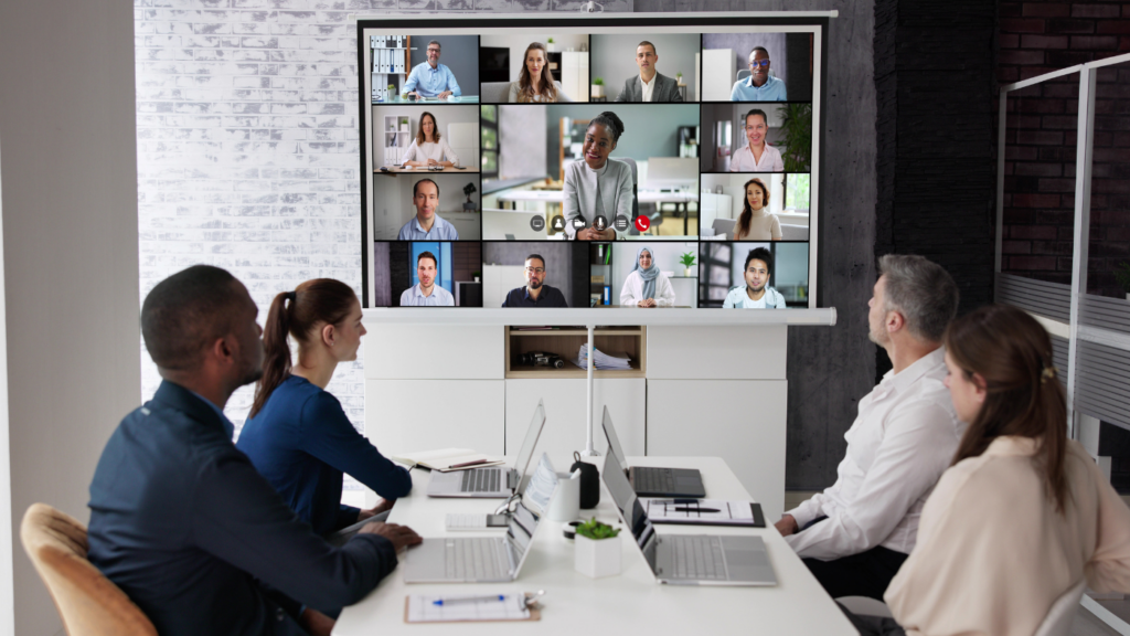 Team collaborating in a modern workplace as a video call fills the screen, supporting digital collaboration platforms and Future of Work tools.