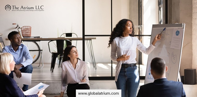 During a professional indoor meeting, a presenter leads workforce planning discussion while the team listens, supporting HR moves for nuclear startups.